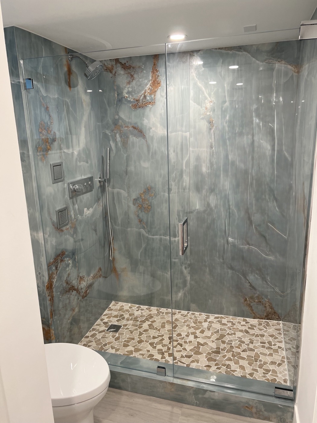 One of the two new bathrooms, with a full-height stone shower surround, pebble floor and frameless glass.