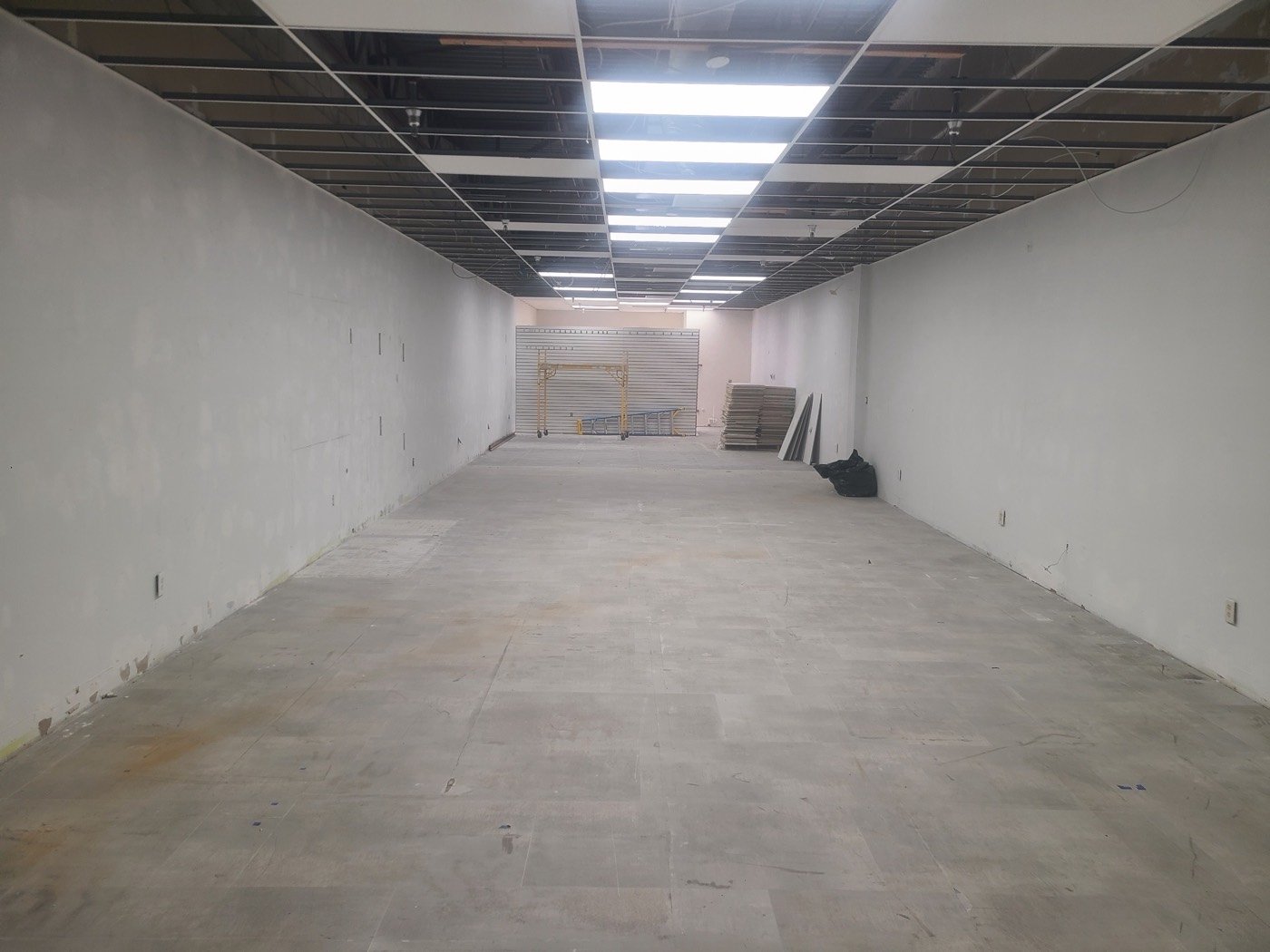 The existing retail space at the start of the build-out, stripped back to bare walls and an open ceiling grid.