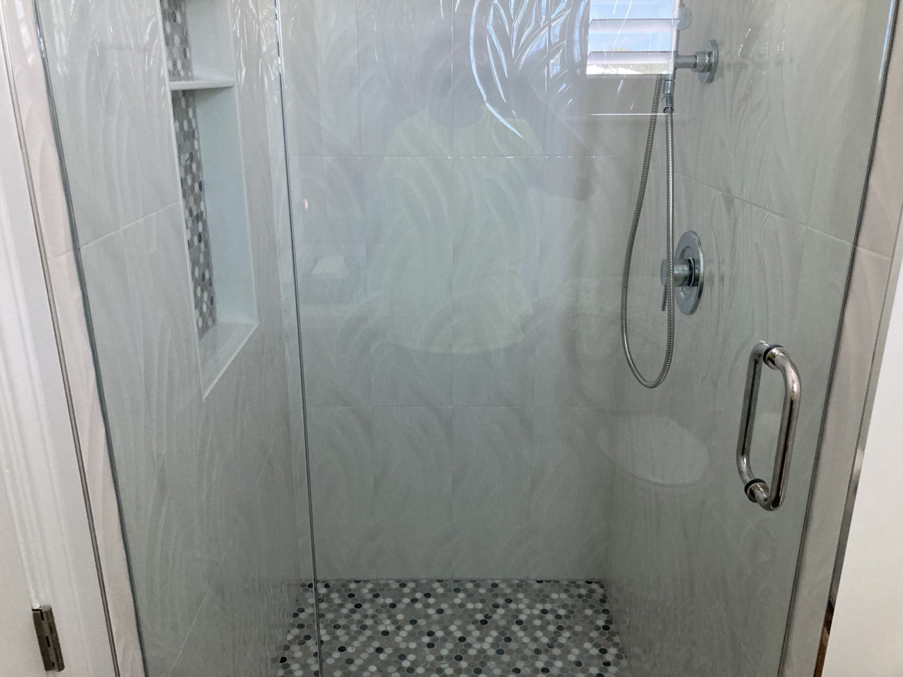 The existing half bath converted to a full bath with a new tiled shower.