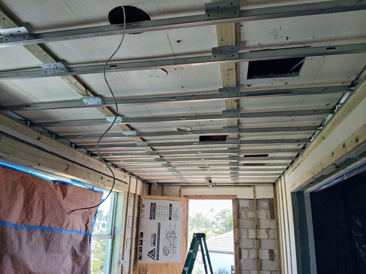 Metal furring and framing at the ceiling, with the new window and door openings framed.