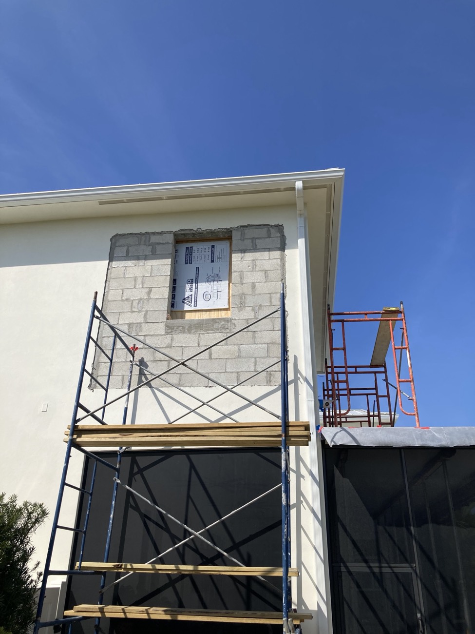 New CMU wall closing in the patio, with the window opening bucked out and the screened porch roof protected below.