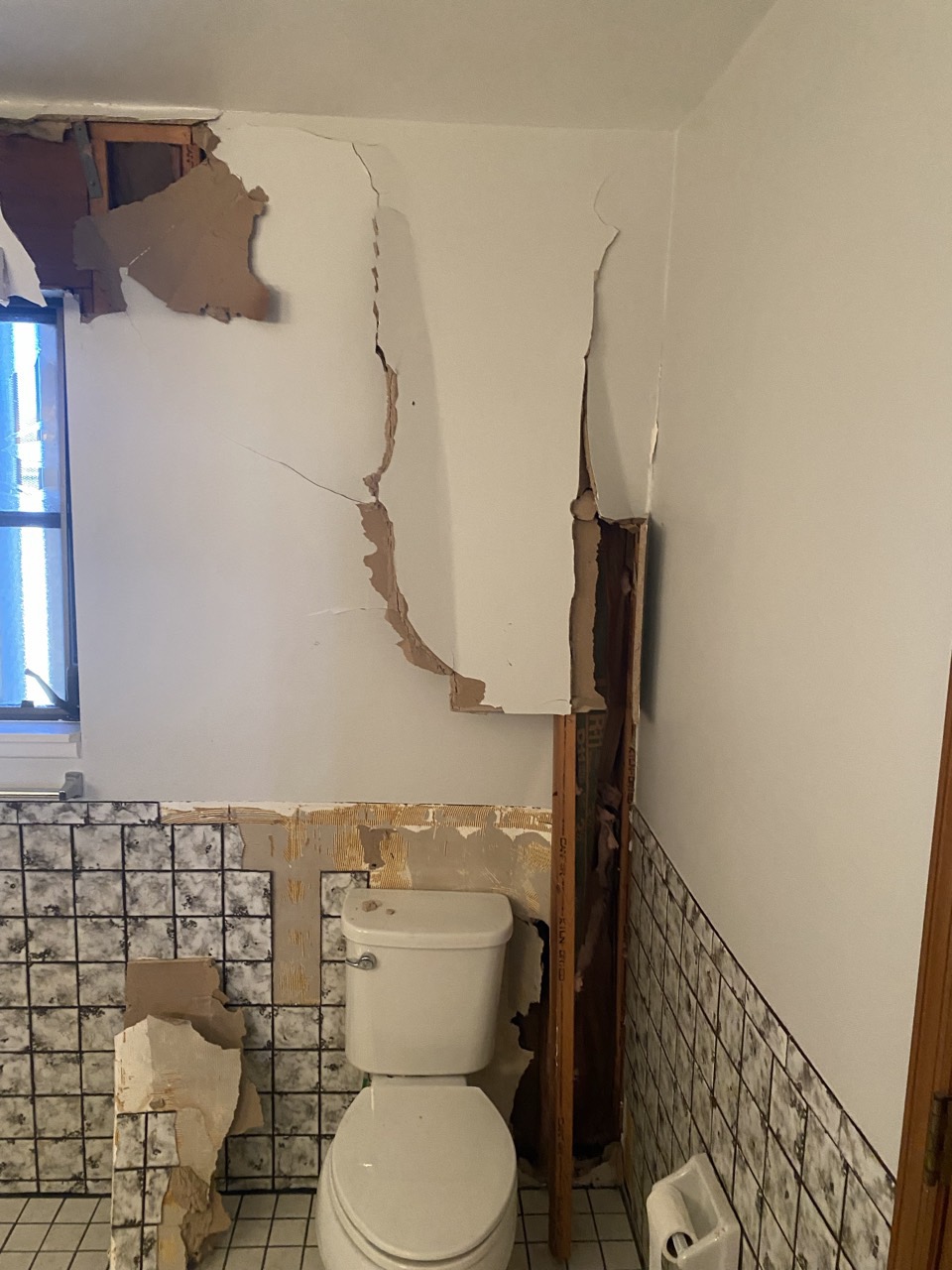 Cracked drywall and damaged tile in the master bathroom before repairs.