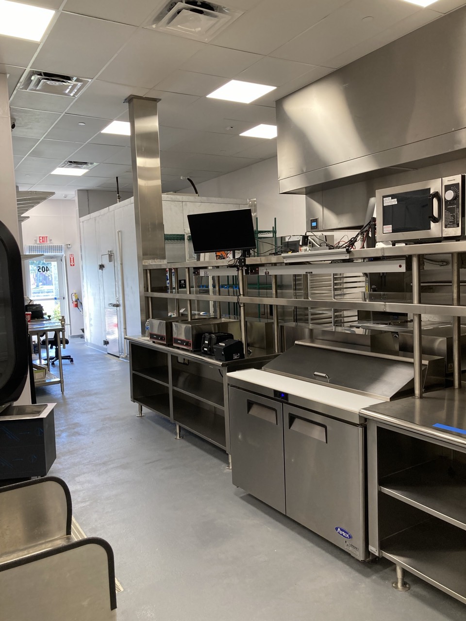 The finished kitchen line, with the exhaust hood, prep stations and walk-in cooler.