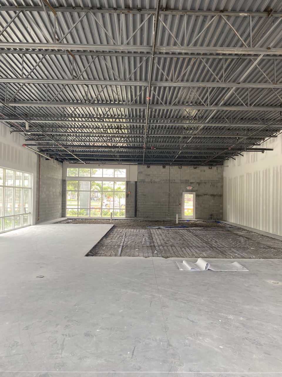 The shell space before construction, with the slab trenched for new plumbing under exposed steel joists.