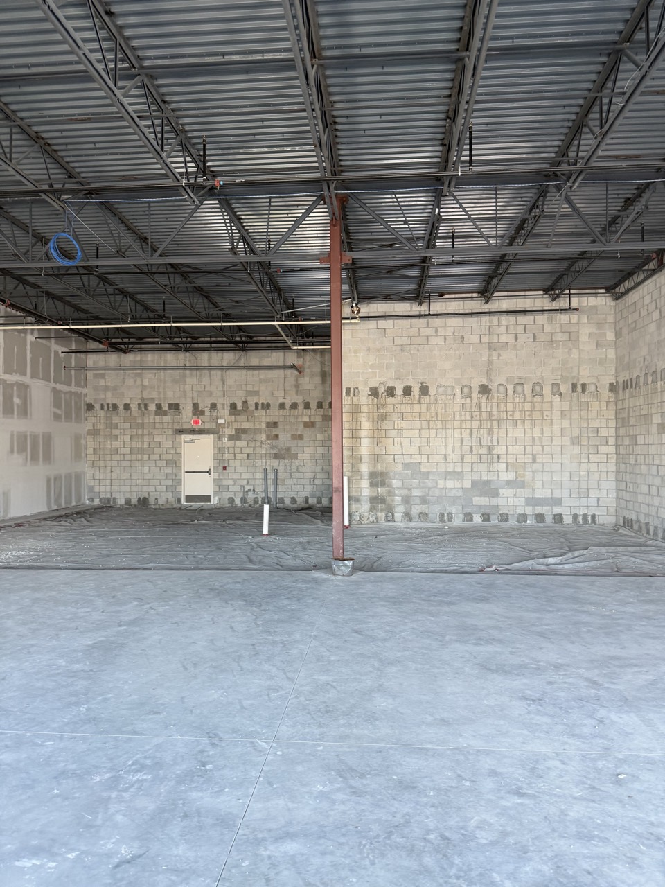 The empty concrete shell before construction: bare block walls, exposed steel deck and a raw slab.