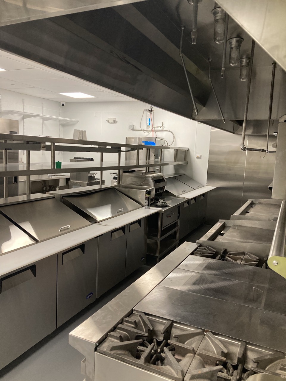 The finished kitchen, with the exhaust hood, cook line and prep stations.